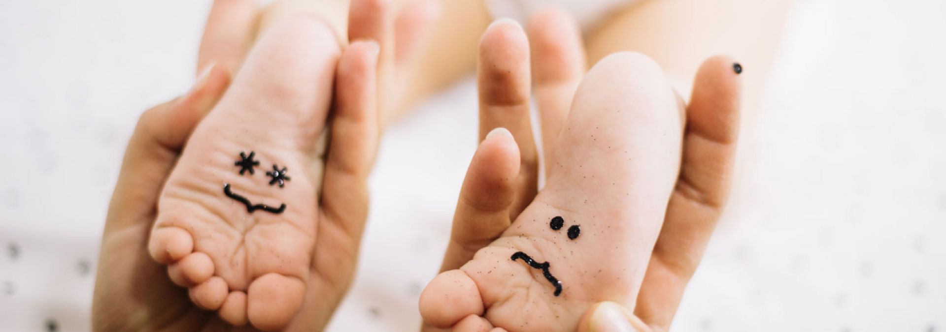 Füße eines Babies mit einem lachenden und einem traurigen Smiley